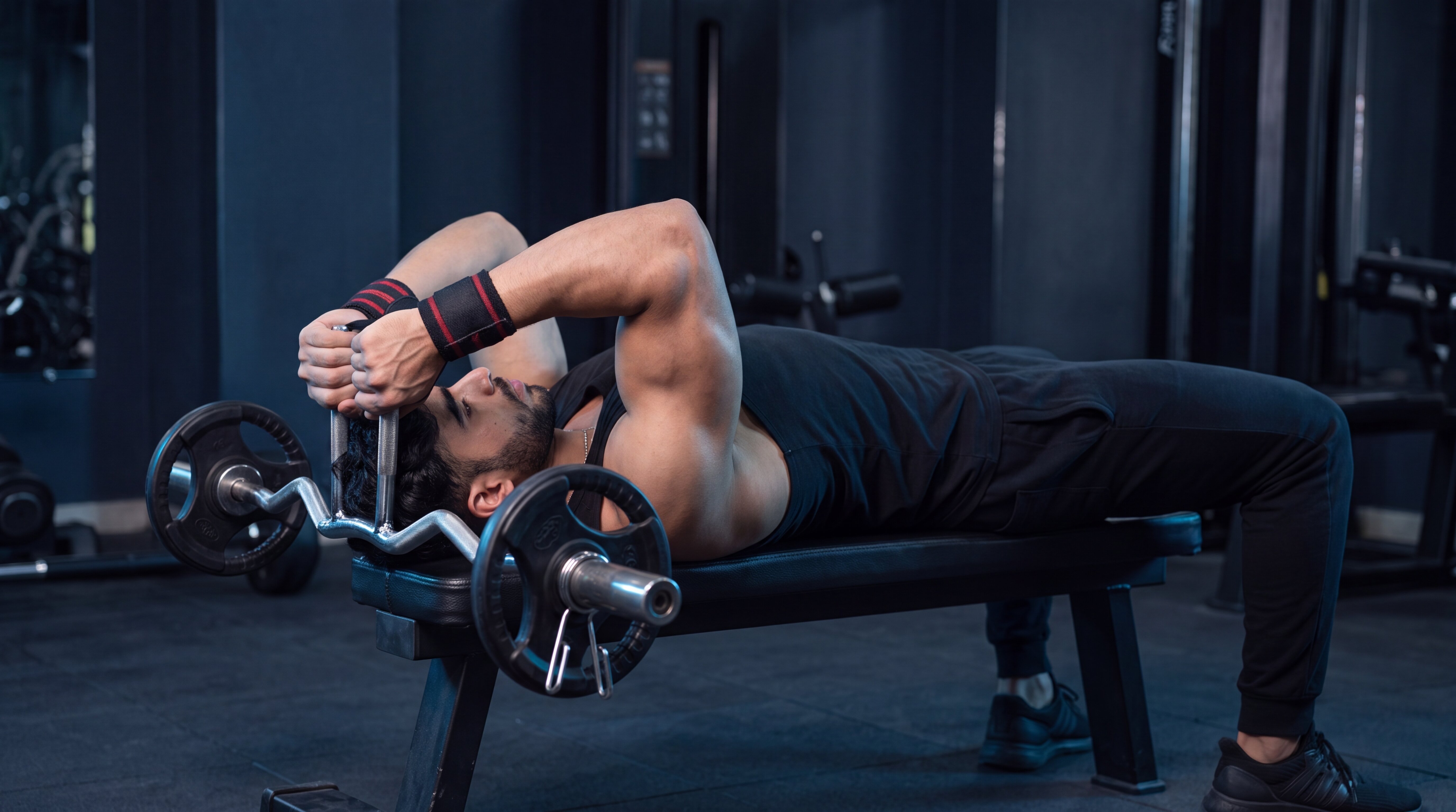 Athlete performing a lying triceps extension with an EZ curl bar